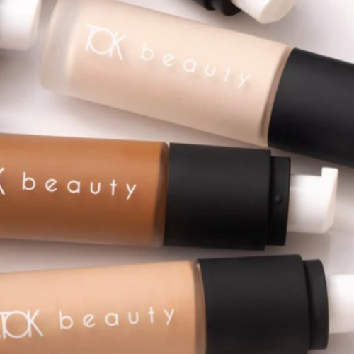 Three TK beauty foundation bottles in different shades on a light background