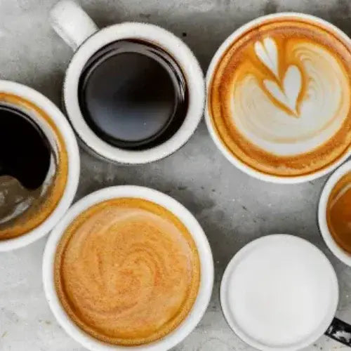 Various cups of coffee with different types of coffee art on a gray surface