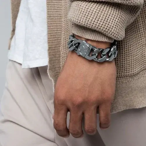 Hand wearing a silver chain bracelet with a neutral background