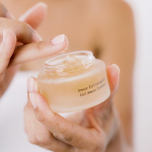 Person holding a jar of skincare gel with a blurred background
