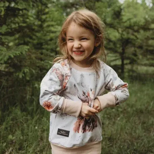 Child wearing a patterned shirt outdoors with trees in the background