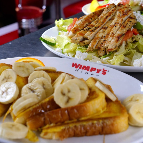 Plate of French toast with bananas and a salad with grilled chicken at Wimpy's Diner.