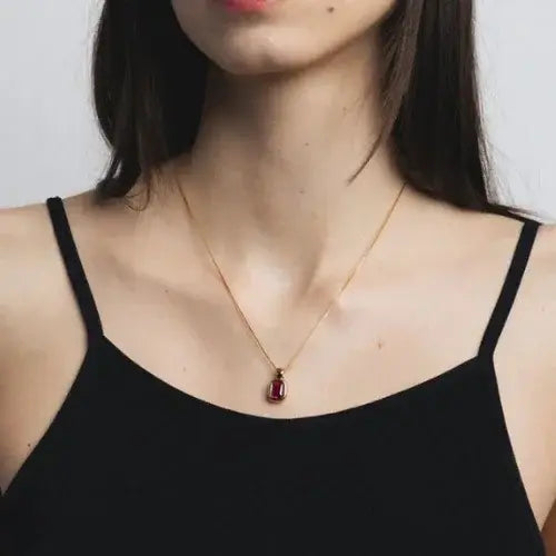 Woman wearing a gold necklace with red gemstone pendant – Contemporary demi-fine jewellery by Canadian brand Wolf Circus