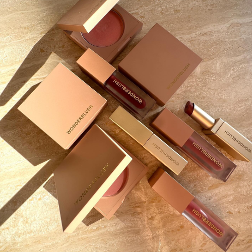 Makeup products including lipsticks and blushes on a beige surface