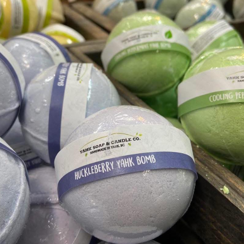 Yank Soap & Candle Co. bath bombs in various colors on a wooden surface.