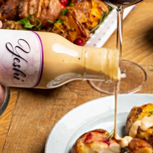 Bottle of Yeshi sauce being poured over food on a wooden table