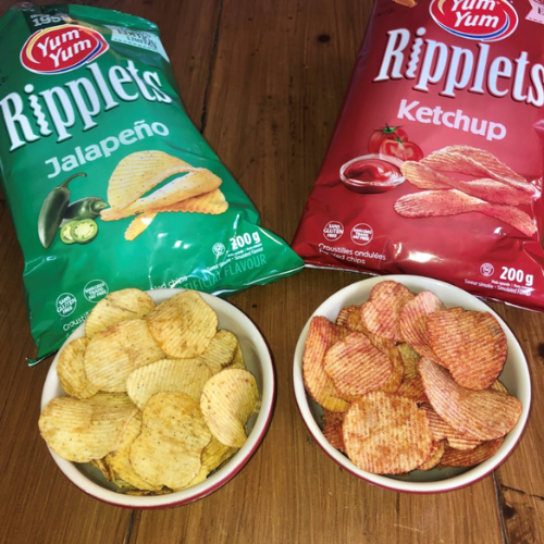 Two bags of Yum Yum Ripplelets chips, one jalapeño and one ketchup, with bowls of chips on a wooden surface.