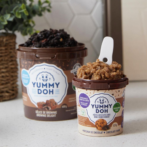 Two containers of Yummy Doh on a countertop with a plant in the background.